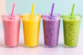 Cuatro smoothies coloridos sobre un fondo pastel