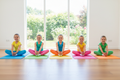 5 girls doing butterfly pose on colorful yoga mats in a bright studio